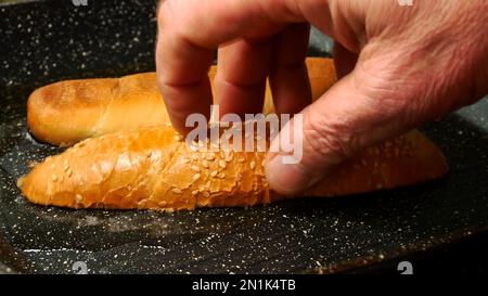 Le pain coupé en tranches pour hot dog est frit dans un récipient à l'huile de cuisson. Préparation de croûtons faits maison dans la cuisine. Gros plan. Banque D'Images