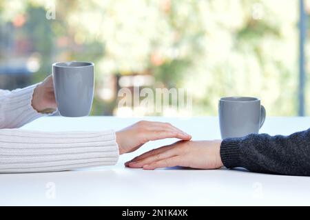 Gros plan d'une femme touchant la main de son partenaire lors d'une date dans une table d'un café ou à la maison Banque D'Images