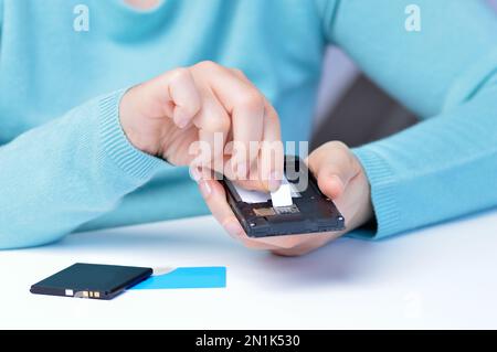 Femme mains mettant la carte sim sur le téléphone Banque D'Images