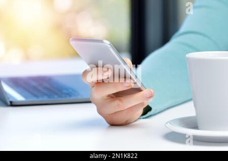 Photo rognée d'une femme d'affaires utilisant un téléphone portable et un ordinateur portable à son bureau Banque D'Images