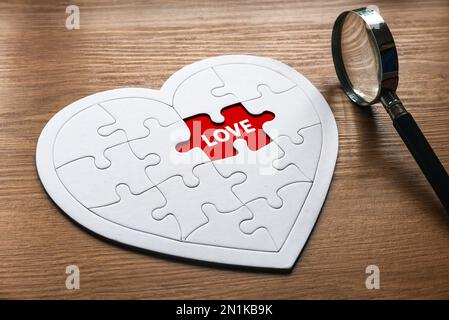 Foyer sélectif de loupe et de forme de coeur puzzle puzzle avec un espace rouge vide écrit avec l'Amour. Banque D'Images