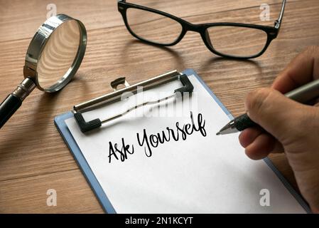 Mise au point sélective de la loupe, des lunettes, et de l'écriture à la main posez-vous sur le presse-papiers avec le papier blanc. Banque D'Images