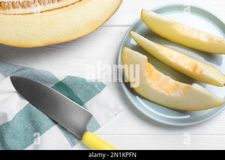 Tranché délicieux melon mûr et couteau sur table en bois blanc, plat Banque D'Images