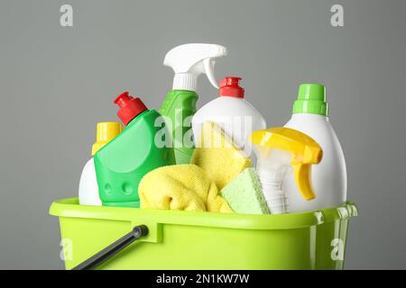 Seau avec produits de nettoyage et outils sur fond gris, gros plan Banque D'Images