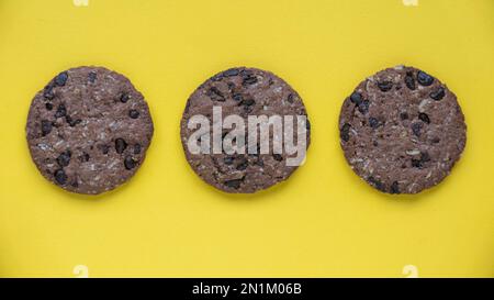 Biscuits d'avoine au chocolat noir isolés sur fond jaune. Banque D'Images