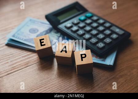 Objectif sélectif de la calculatrice, de l'argent et du cube en bois écrit avec l'alphabet EAP ( Programme d'aide aux employés ). Banque D'Images