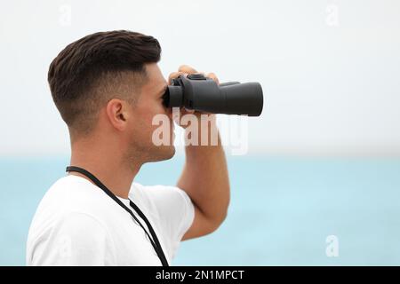 Beau maître-nageur mâle avec binoculaire près de la mer Banque D'Images