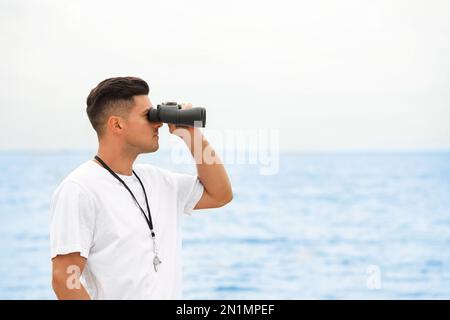 Beau maître-nageur mâle avec binoculaire près de la mer Banque D'Images