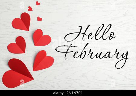 Carte de vœux avec texte Bonjour février. Cœur en papier rouge sur fond blanc en bois, plat Banque D'Images