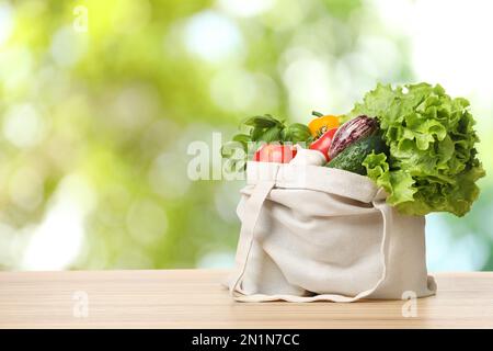 Légumes frais dans un sac en tissu sur une table en bois sur fond flou. Espace pour le texte Banque D'Images