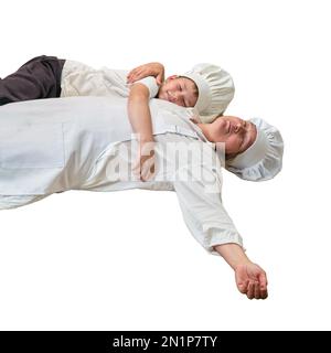 Maman et son fils drôles se détendent dans la cuisine après la cuisson, isolés sur un fond blanc. Une femme fatiguée et un garçon sont allongés sur le sol de la cuisine Banque D'Images