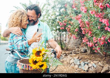 Homme et femme en plein air appréciant l'amour et romantique activités de loisirs en plein air ensemble en se serrant et en utilisant le téléphone mobile. Relation mature style de vie. Happ Banque D'Images