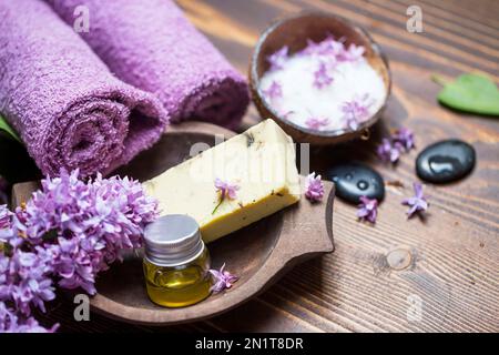 Spa avec savon naturel, huile pure essentielle au lilas, sel de mer et pierres de massage avec serviettes en coton doux pour se faire dorloter Banque D'Images
