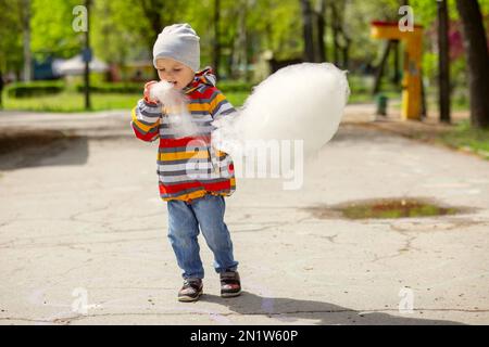 Un enfant dans un parc d'attractions mange des bonbons en coton Banque D'Images