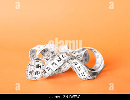 Ruban de mesure blanc sur fond orange, gros plan Banque D'Images