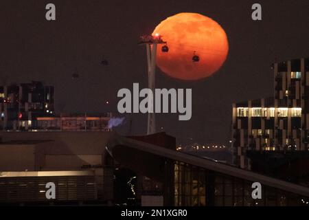 Londres, Royaume-Uni. 6th février 2023. Météo au Royaume-Uni: 99,1% pleine lune fait des silhouettes de passage de téléphériques, également connu sous le nom de téléphérique d'IFS Cloud dans l'est de Londres. Credit: Guy Corbishley/Alamy Live News Banque D'Images