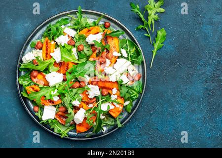 Délicieuse salade de pêche grillée avec fromage, noisettes et arugula sur fond bleu, vue de dessus Banque D'Images