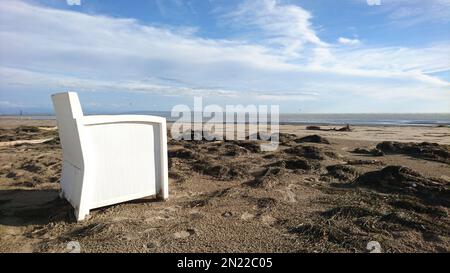 Luxueux fauteuil de bar blanc sur une plage de sable vide avec algues délavées et vue sur la mer et le ciel bleu. Photo prise à Grado, Italie Banque D'Images