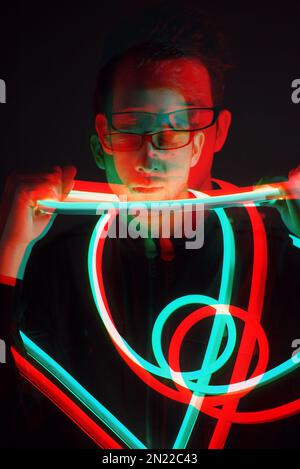 Glitch Double Exposure Portrait futuriste en beau jeune hipster homme avec des lunettes tendance sur enveloppé de ruban lumineux au néon Banque D'Images