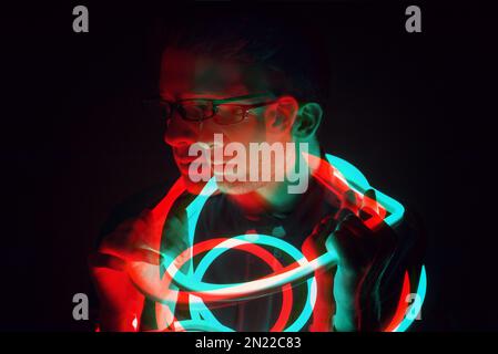 Glitch Double Exposure Portrait futuriste en beau jeune hipster homme avec des lunettes tendance sur enveloppé de ruban lumineux au néon Banque D'Images