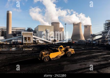 Une usine lourde raclant le charbon d'une cheminée de combustible fossile dans une grande centrale au charbon pour brûler pour produire de l'électricité non renouvelable Banque D'Images