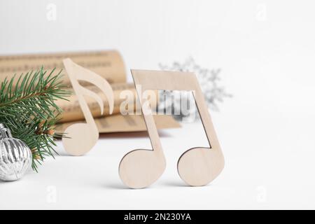 Note de musique en bois et branche de sapin avec boule de Noël sur fond blanc Banque D'Images