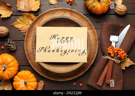 Mise en place de table saisonnière avec carte Happy Thanksgiving Day et citrouilles sur table en bois, pose à plat Banque D'Images