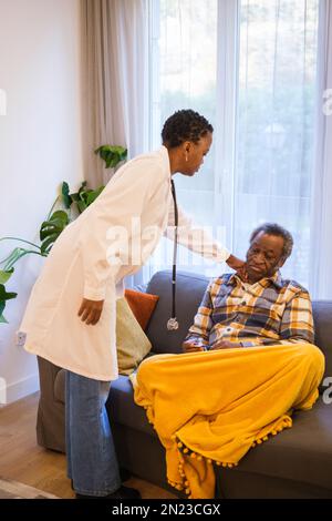 Femme médecin à cheveux courts inspectant sa patiente, retraité homme âgé qui est malade. Concept : soins de santé, médecin voyageur, maladie Banque D'Images