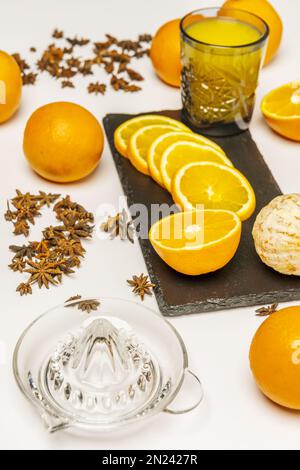 Une vie encore remplie de jus d'orange frais entouré de tranches et d'oranges entières, avec une centrifugeuse en verre, des oranges coupées et des oranges coupées Banque D'Images