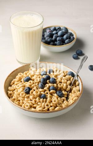 bol de céréales pour le petit-déjeuner, anneaux de miel et lait sur une table de cuisine blanche Banque D'Images