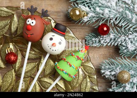 Délicieux gâteaux à thème de Noël et branches de sapin avec boules sur table en bois, plat Banque D'Images