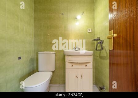 salle de bains classique avec mobilier blanc, tiroirs et portes, porte-racine en sapelli verni et carrelage vert Banque D'Images