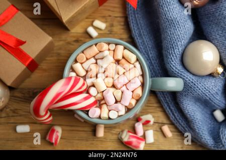 Composition de plat avec tasse de cacao savoureux, Cannes de bonbons et cadeaux de Noël sur table en bois, plat Banque D'Images