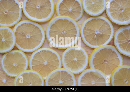 Fond de tranches de citrons jaunes finement tranchées sur une planche de bois Banque D'Images