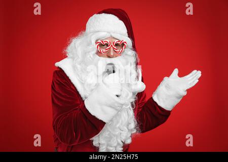 Père Noël avec microphone sur fond rouge. Musique de Noël Banque D'Images