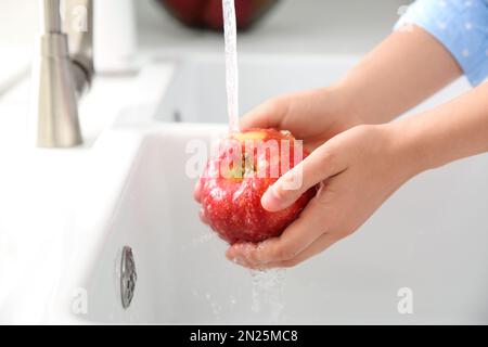 Femme lavant de la pomme rouge fraîche dans l'évier de cuisine, gros plan Banque D'Images