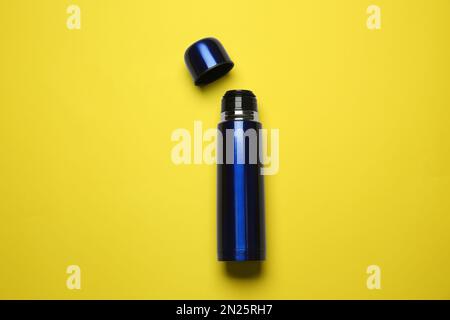 Thermos en métal bleu sur fond jaune, vue de dessus Banque D'Images