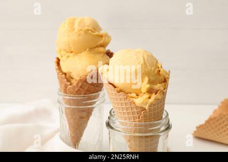 Délicieuse glace jaune dans des cônes de cachets et des pots de verre sur la table, en gros plan Banque D'Images