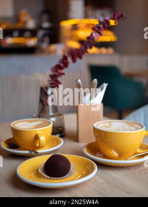 Tasses de café jaunes avec boisson et gâteau au chocolat sur la table dans le café, format vertical. Café agréable, concentration sélective Banque D'Images