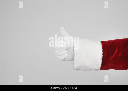 Père Noël montrant le pouce sur fond gris clair, gros plan de la main Banque D'Images