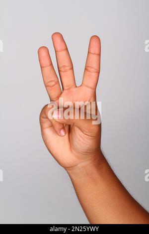 La main de jeune homme montre le fond isolé du doigt d'index numéro trois , numéro trois Banque D'Images