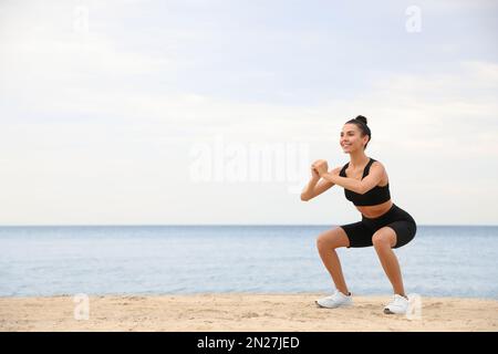 Jeune femme faisant de l'exercice sur la plage, espace pour le texte. Entraînement du corps Banque D'Images