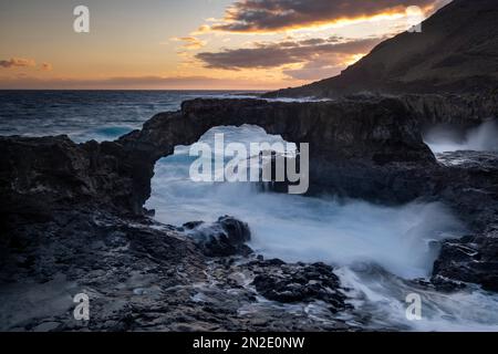 Lever du soleil à l'arche de roche Charco Manso, El Hierro, îles Canaries, Espagne Banque D'Images