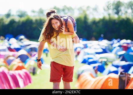 Laissez-moi vous donner un ascenseur... un jeune homme transportant sa petite amie à travers un camping. Banque D'Images