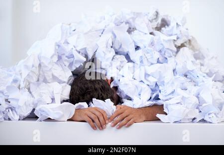 Les paperworks s'accumulent. un homme d'affaires enterré sous une pile de documents écroulés. Banque D'Images