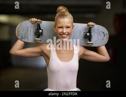 Permutation de la scène pour un skateboard. Une jeune ballerine tenant un skateboard derrière son cou. Banque D'Images