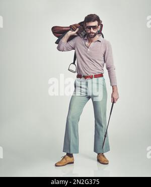 C'est parti !Photo en studio d'un homme attrayant en style rétro 70s portant une selle et une récolte d'équitation. Banque D'Images