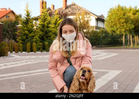 Femme en masque de protection avec le Cocker anglais en plein air. Chien de marche pendant la pandémie de COVID-19 Banque D'Images