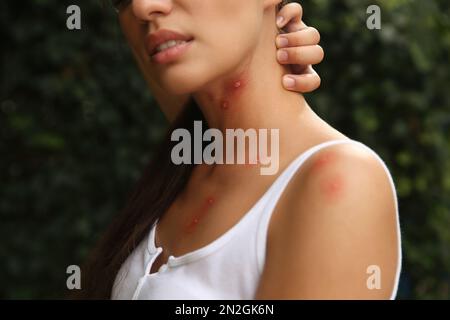 Femme se grattant le cou avec des piqûres d'insectes dans le parc, en gros plan Banque D'Images