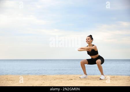 Jeune femme faisant de l'exercice sur la plage, espace pour le texte. Entraînement du corps Banque D'Images